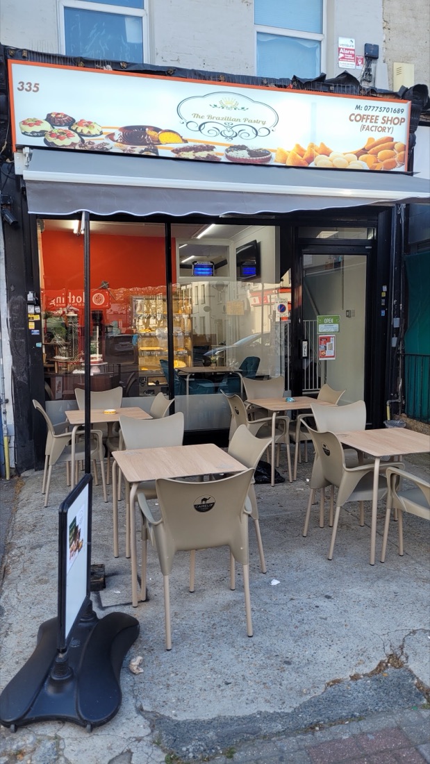 The orange shopfront of The Brazilian Pastry on Barking Road with pavement café tables